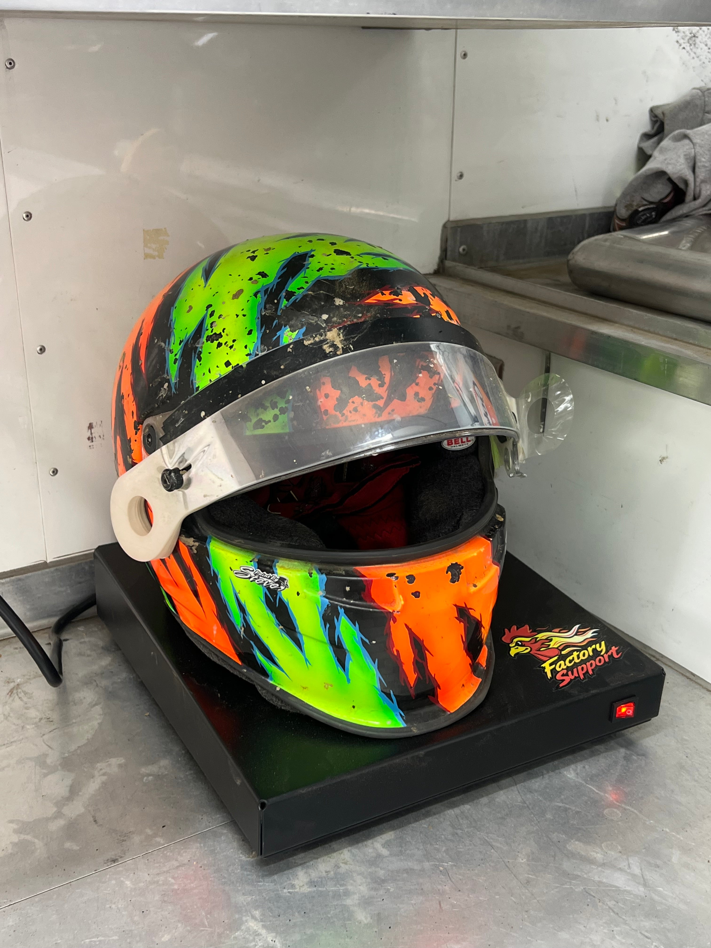 Colorful sprint car helmet on Factory Support V1 Helmet Dryer in trailer