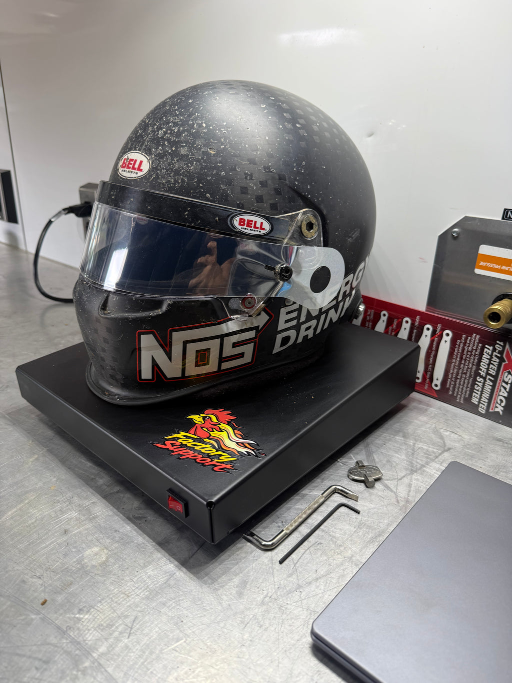 Bell racing helmet sitting on Factory Support V1 Helmet Dryer in shop