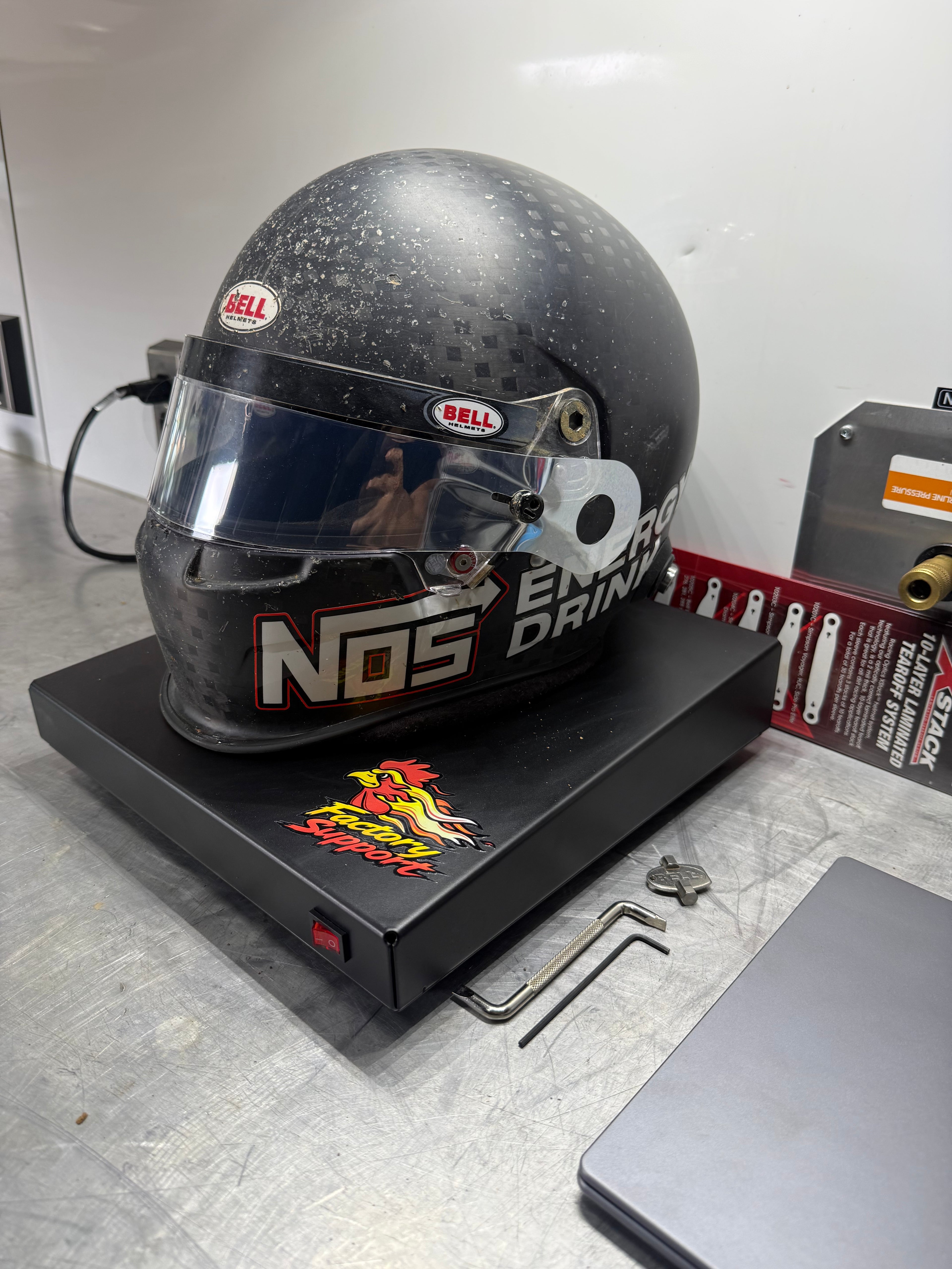 Bell racing helmet sitting on Factory Support V1 Helmet Dryer in shop